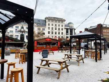 Manchester, İngiltere - 09 Kasım 2025: Manchester 'da ahşap piknik masaları ve gıda tezgahlarının yer aldığı canlı bir şehir pazarı.