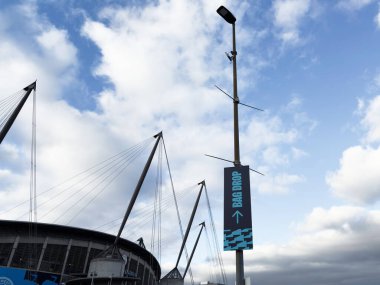 Manchester, İngiltere - 16 Kasım 2025: Manchester Stadyumu 'nda uzun bir direk pankartı ve modern mimarinin yer aldığı parlak bir gün.