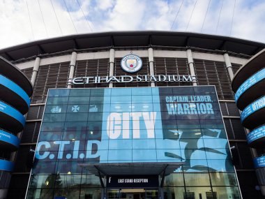 Manchester, İngiltere - 16 Kasım 2025: Manchester Citys Etihad Stadyumu 'nun dış görünüşü büyük mavi pankartı ve modern cam cepheleriyle.