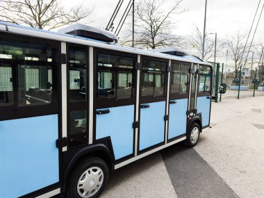 Manchester, İngiltere - 16 Kasım 2025: Manchester Stadyumu yakınlarında çıplak kış ağaçları olan açık mavi bir tramvay.