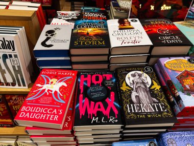 Manchester, İngiltere - 15 Kasım 2025: Parlak, çeşitli ciltli ve ciltli başlıklar bir kitapçının rafında, renkli kapak resimleri ve edebi hisler sergileniyor.