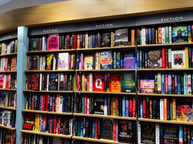 Manchester, İngiltere - 15 Kasım 2025: Canlı bir kitapçıda rafları karşılayan renkli kurgu kitapları dizisi.