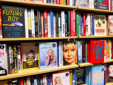 Manchester, İngiltere - 15 Kasım 2025: Ahşap bir raftaki renkli kitap kapakları çeşitli başlık ve türlere sahip canlı bir kitapçı sahnesi yarat.