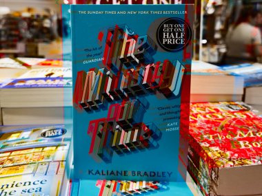 Manchester, İngiltere - 15 Kasım 2025: Matt Haig 'in Gece Yarısı Kütüphanesi' nin parlak turkuaz kopyası kalabalık bir kitapçıda sergilendi.