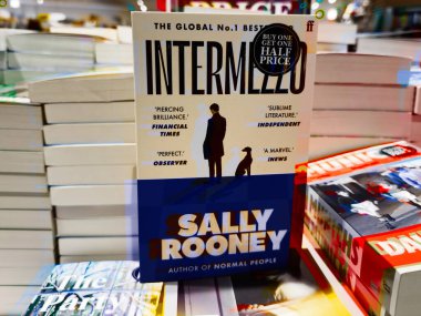 Manchester, İngiltere - 15 Kasım 2025: Sally Rooney 'nin Hardcover Intermello adlı kitabı yığılmış başlıklar ve renkli ışıklandırmalar arasında sergileniyor.