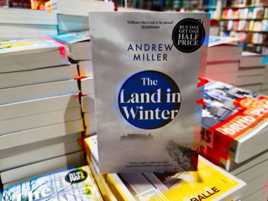 Manchester, İngiltere - 15 Kasım 2025: Andrew Miller 'ın The Land in Winter kitabının ciltli kapağı renkli kitapçılar arasında sergileniyor.