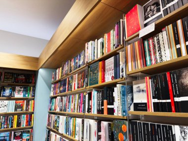 Manchester, İngiltere - 15 Kasım 2025: Parlak, davetkar raflar çeşitli kitapları barındırıyor, rahat, renkli bir kitapçı ortamı yaratıyor.