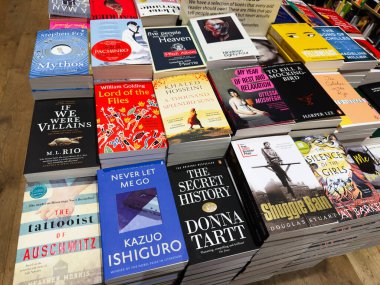 Manchester, İngiltere - 15 Kasım 2025: Parlak bir kitapçıda istiflenmiş kitap masalarında popüler roman ve çok satan kitapların renkli gösterimi.