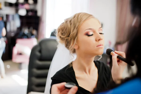 Joven novia rubia aplicando maquillaje de boda por maquillador —  Fotos de Stock