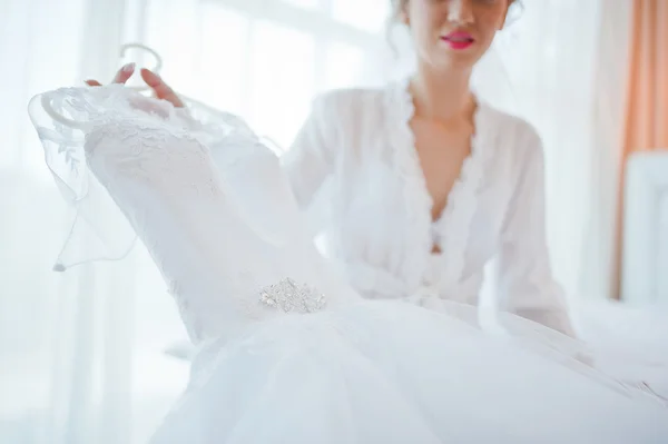 Нежная блондинка невеста на диване с свадебным платьем — стоковое фото