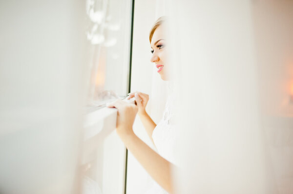 нежная блондинка невеста на занавесках нежная поза
