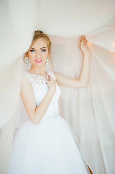 Jemná blondýnka nevěsta na záclony nabídku představují — Stock fotografie