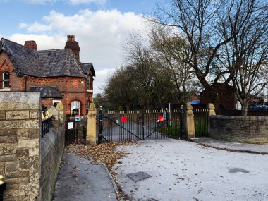 Manchester, İngiltere - 16 Kasım 2025: Manchester 'da sonbahar yaprakları ve ağaçları olan tuğla bir binanın yanında giriş kapısı.