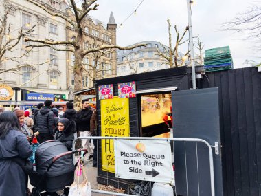 Manchester, İngiltere - 16 Kasım 2025: Manchester sokak pazarı şenlik tezgahları ve kuyruk levhalarında aileler, arkadaşlar ve müşterilerle dolu.