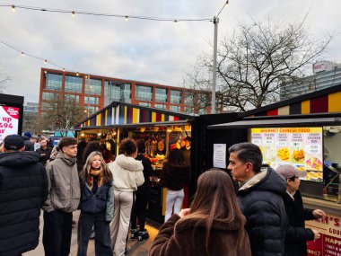 Manchester, İngiltere - 16 Kasım 2025: Manchester 'da kalabalık akşam ışıkları altında çeşitli sokak yemeklerinin tadını çıkarıyor.