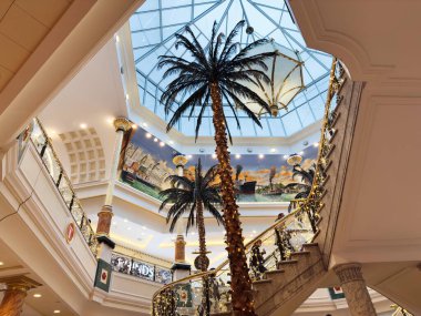 Stretford, İngiltere - 15 Kasım 2025: Palmiye ağaçları, duvar resimleri ve cam kubbeli şık Manchester Trafford Centre atriyumu, sıcak dekoratif ışıklarla yıkandı.