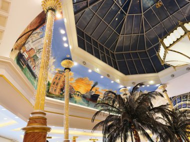 Stretford, İngiltere - 15 Kasım 2025: Manchester, İngiltere 'de cam çatı, altın sütunlar, tropikal bitkiler ve duvar resimlerinin yer aldığı Manchester' daki bir otel lobisindeki kapalı Trafford Center atrium sahnesi.