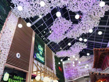 Stretford, İngiltere - 15 Kasım 2025: Canlı Manchester Chit 'N' Chaat iç pazar çiçekli tavan kurulumları, yuvarlak ışıklar ve renkli tabelalar.