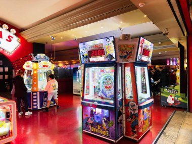 Stretford, İngiltere - 15 Kasım 2025: Manchester 'da çocuklar ve yetişkinlerin renkli oyun makineleri ve neon ışıklarının keyfini sürdüğü parlak atari sahnesi.