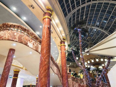 Stretford, İngiltere - 15 Kasım 2025: Manchester İngiltere 'de kırmızı mermer sütunları, palmiye ağaçları ve dekoratif ışıkları olan zarif lobi.