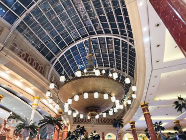 Stretford, İngiltere - 15 Kasım 2025: Lüks Trafford Center avizesi şık bir Manchester lobisinde palmiye ağaçları ve gösterişli dekorları olan cam bir avluya hakim.