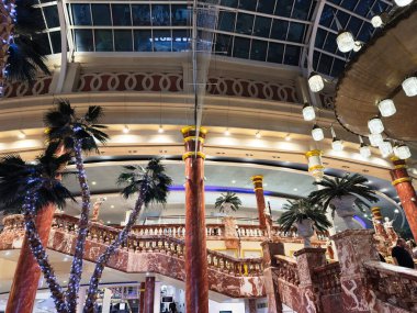 Stretford, İngiltere - 15 Kasım 2025: Mermer merdiven, palmiye ağaçları ve büyük bir avluda yanıp sönen ışıklar ile Trafford Center iç mimarisi.