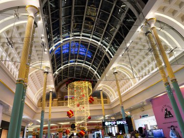 Stretford, İngiltere - 15 Kasım 2025: Manchester, İngiltere 'deki süslü bir Trafford Center alışveriş merkezi iç mimarisi kemerler, altın sütunlar ve asılı tatil ışıkları.