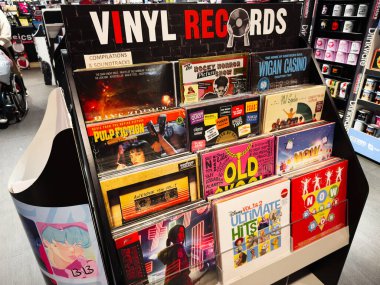 Stretford, İngiltere - 15 Kasım 2025: Manchester 'da renkli kapaklı işlek bir müzik mağazasında parlak vinil albüm rafları.