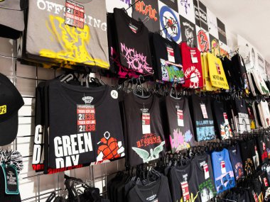 Stretford, İngiltere - 15 Kasım 2025: Manchester 'da bir mağazada raflardaki grafiksel tişörtler, parlak tasarımlar, kalın bant logoları, şehir tarzı.