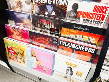Stretford, İngiltere - 15 Kasım 2025: Manchester 'da canlı ve nostaljik bir müzik dükkanında renkli vinil kollar ve klasik albüm rafları.