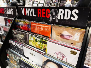 Stretford, İngiltere - 15 Kasım 2025: Meşgul bir iş atmosferinde ikonik bantlar ve klasik albümler içeren Manchester vinil plak sergisi.