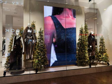 Stretford, İngiltere - 15 Kasım 2025: Manchester 'da mankenler, ışıklandırılmış Noel ağaçları ve parlak bir dijital ekran içeren şenlikli mağaza.