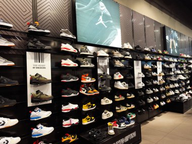 Manchester, İngiltere - 19 Kasım 2025: Manchester 'daki bir mağazada spor ayakkabıları, moda ve hediye seçeneklerinin sergilendiği geniş spor ayakkabı duvarı.