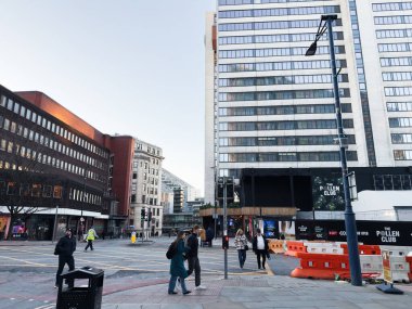 Manchester, İngiltere - 19 Kasım 2025: Manchester kentsel şehir merkezi açık gökyüzü altında yayalar, modern mimariler ve inşaat engellerini gösteriyor.