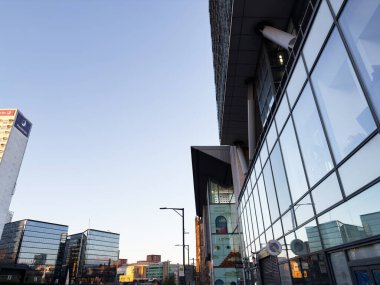 Manchester, İngiltere - 19 Kasım 2025: Manchester 'da çağdaş cam mimarisi ve parlak gökyüzü ile şehir sahnesi.