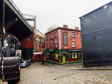 Manchester, İngiltere - 27 Kasım 2025: Manchester, İngiltere 'de kaldırımlı cadde, tuğlalı Salisbury barları ve canlı yeşil budanmış vitrin.