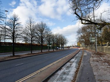 Manchester 'da sakin bir şehir caddesinde çıplak ağaçlar, tramvay rayları ve açık bir gökyüzü var..
