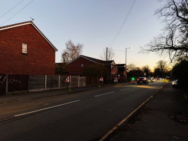 Karanlık çöktüğünde Manchester 'da sakin bir banliyö caddesinde yol tabelası ve park halindeki arabaların olduğu.