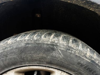 Tozlu bir lastiğin üzerini kapayın. Temiz bir lastik izi var. Gölgeli, kel bir tekerleğin içinde..