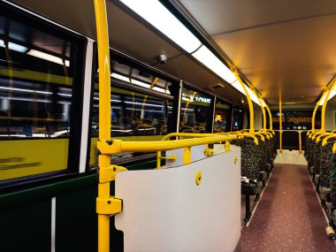 Sarı raylı, desenli koltuklu ve modern ışıklandırmalı bir Manchester otobüsünün içi..