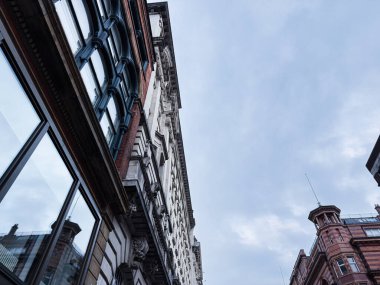 Manchester 'ın tarihi mimarisinin düşük açılı görüntüsü, açık mavi gökyüzüne karşı kırmızı tuğlalar soluyor..