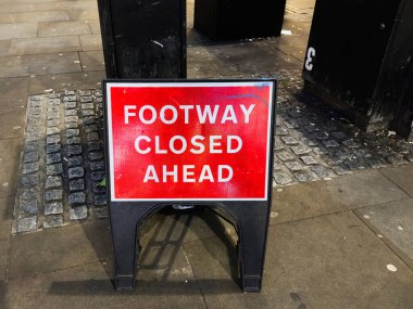 Taşınabilir bir stanttaki parlak kırmızı uyarı işareti Manchester 'daki kaldırımı kapatıyor..