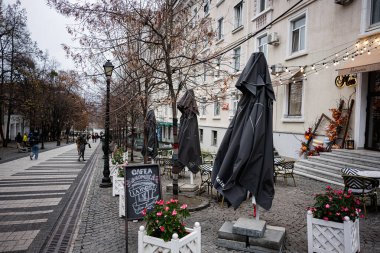 Chisinau, Moldova - 22 Kasım 2025: Moldova 'da kafeterya oturma, sicim ışıkları, bitkiler ve sonbahar havası olan rahat kentsel sokak sahnesi.
