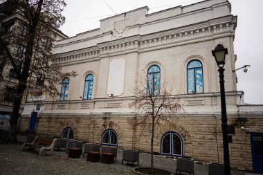 Chisinau, Moldova - 22 Kasım 2025: Kişinev 'de tarihi bir cephe, mavi kemerli pencereler ve bankların yer aldığı sakin bir kent manzarası. Merkezi Sinagog Chabad Lubavitch