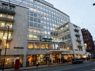 Manchester, İngiltere - 10 Aralık 2025: Manchester UK 'deki modern ofis cephesinde birlikte çalışan mekanlar, cam pencereler, yayalar ve kentsel enerji.