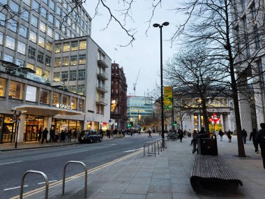 Manchester, İngiltere - 10 Aralık 2025: Manchester 'da alışveriş caddesi, aydınlatma mağazaları, festival dekorasyonları ve yürüyen insanların yer aldığı şehir sahnesi.