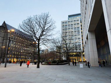 Manchester, İngiltere - 10 Aralık 2025: Manchester 'da bir halk plazası, çağdaş mimari ve yayaların yer aldığı akşam sahnesi.