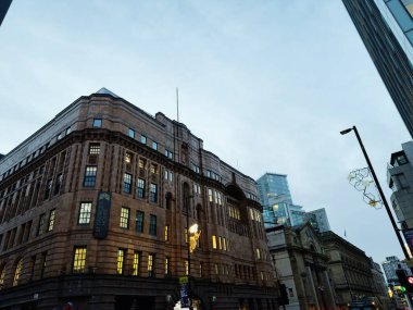 Manchester, İngiltere - 10 Aralık 2025: Tarihi Manchester St Georges Binası, arka planda modern cam kuleler ve sokak ışıkları.