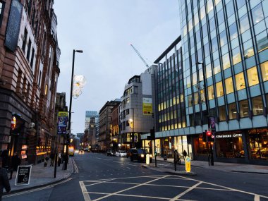 Manchester, İngiltere - 10 Aralık 2025: Camdan ofisleri, trafiği, yayaları ve Starbucks 'ı olan Manchester kentsel caddesi.