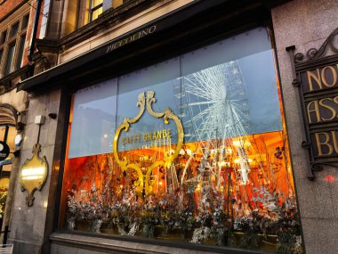 Manchester, İngiltere - 10 Aralık 2025: Manchester 'da sıcak turuncu iç ve süslü altın çerçeveli bir kafe mağazası.